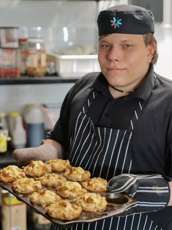 Jack is in the kitchen, dressed in his chef uniform, holding a tray of mini quiches just pulled from the oven. 