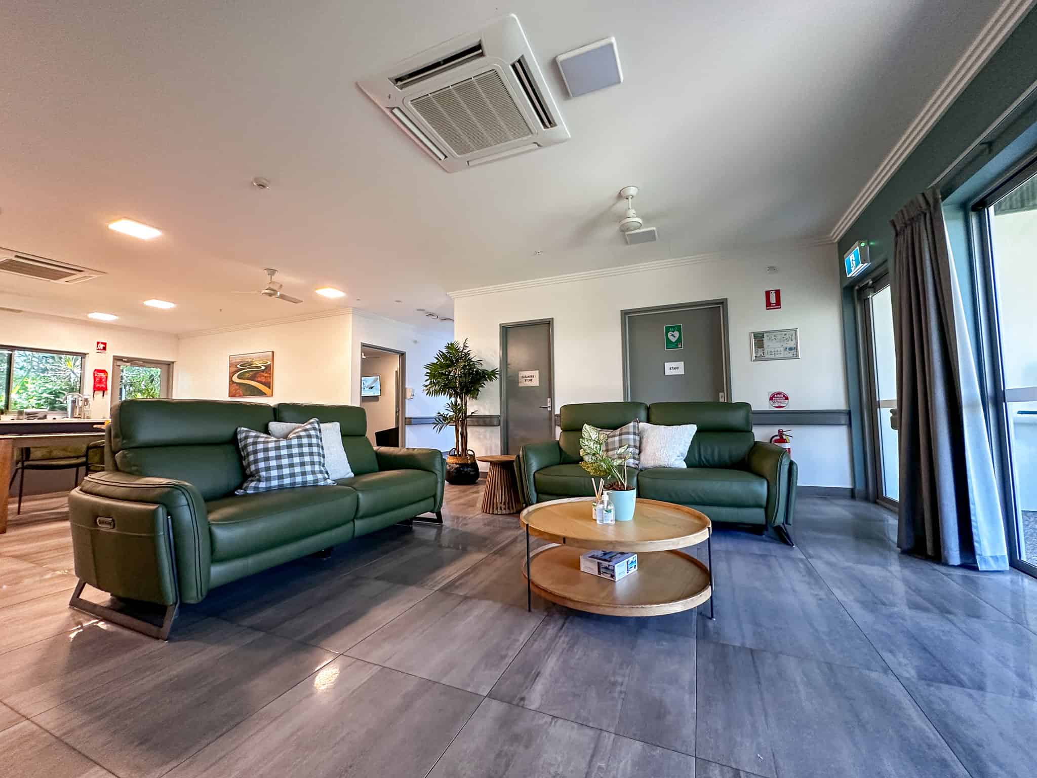 A wide angle view of the loungeroom, featuring two green leather lounges and a round coffee table.