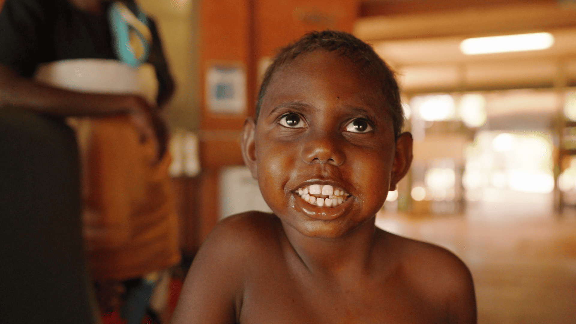 A young Indigenous boy is looking up and smiling.